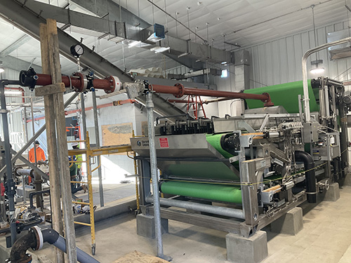Belt Filter Press Discharges Dewatered Biosolids to Transfer Screw Conveyor