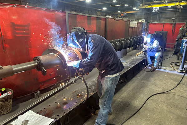 Multiple Welders Apply Hardsurfacing to Carrying Face of Screw